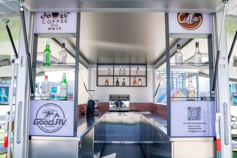 Good MFG coffee trailer, front view, with shelving, lighting, countertops, and equipment.