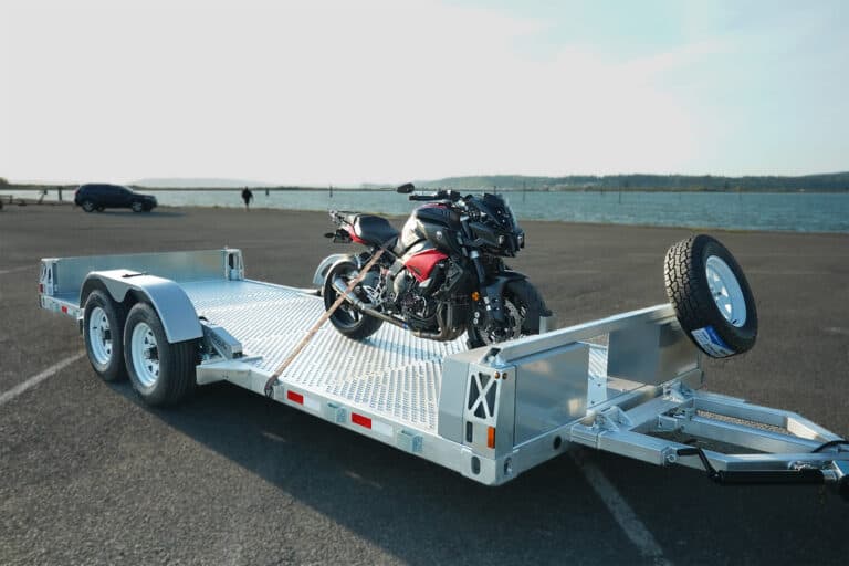 A motorcycle attached to a Good Flatbed Trailer, ready to transport and tow.