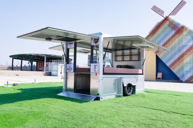 A photo of a Good Trailer converted into a coffee stand, with lift panels, entry doors, counters, and shelves.