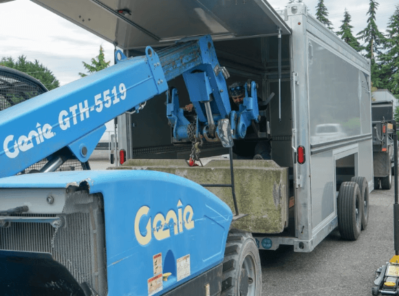 A Genie places a heavy load into an HDX trailer.