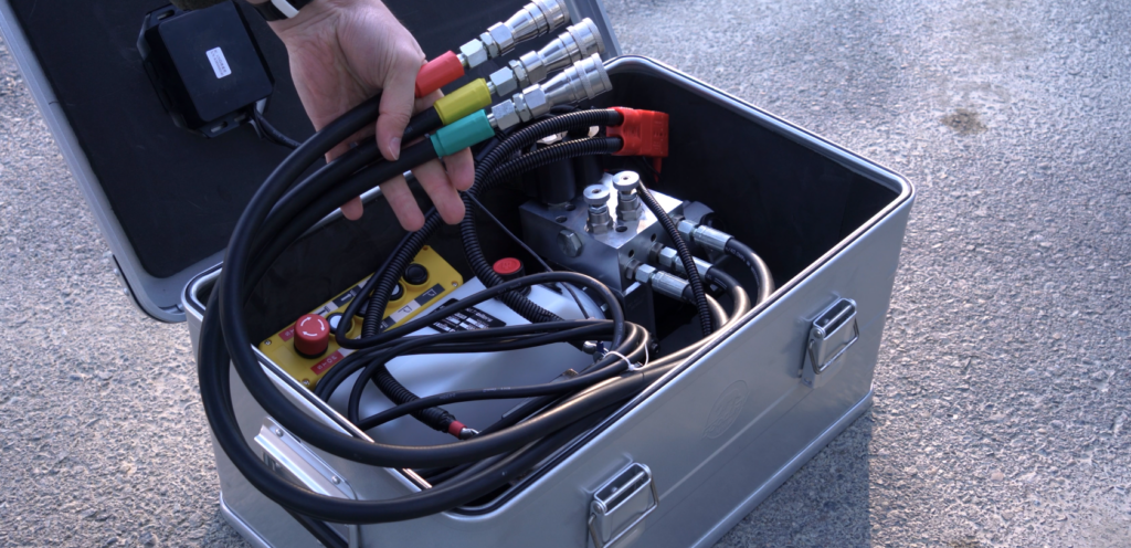 Portable hydraulic pump with color coded hoses.