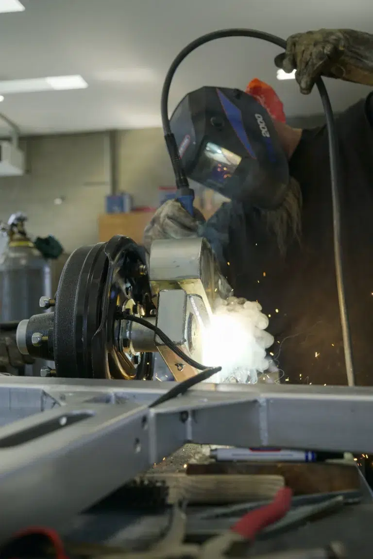 A welder working on a trailer needs repair.