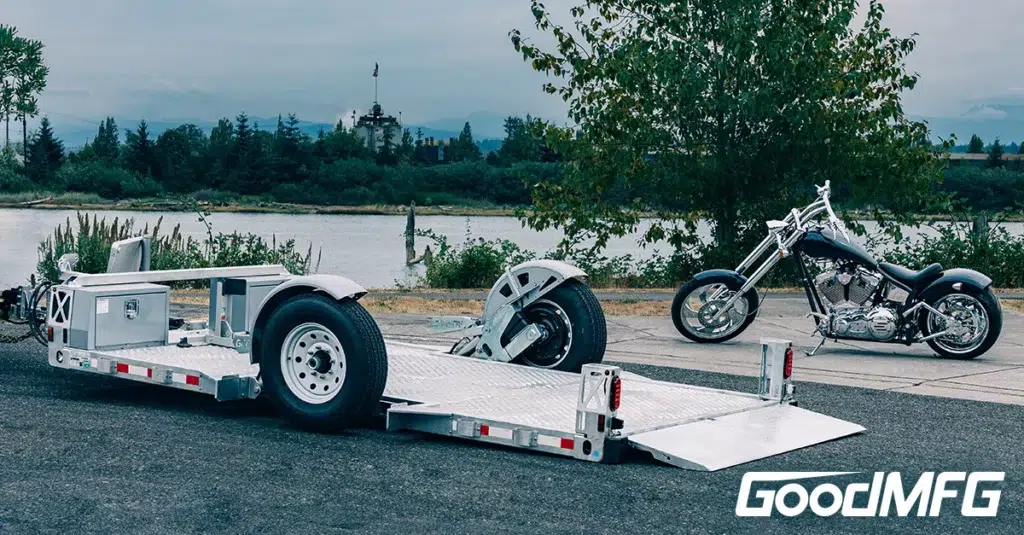 A motorcycle sits next to a flatbed trailer